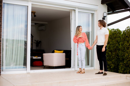 Handsome ymiling young couple in love walking in front of house brick wallの写真素材