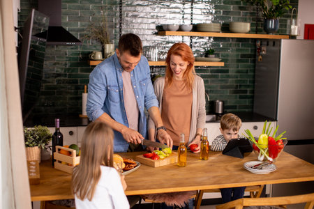 Happy young family preparing vegetables in the kitchenの写真素材