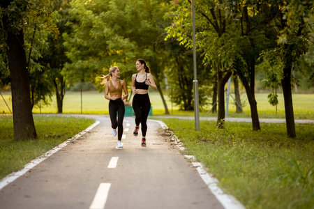 Two pretty young women running on a lane in the park