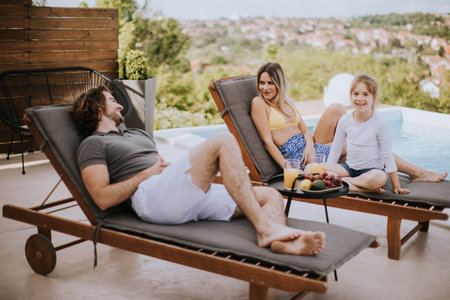 Handsome young family relaxing by the swimming pool in the house backyardの写真素材