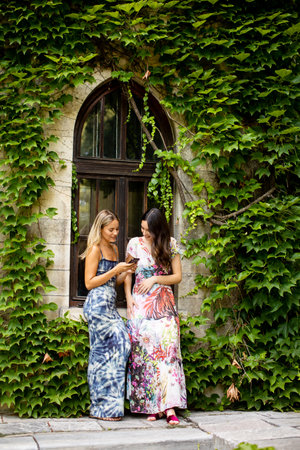Pretty young women using mobile phone by old house with ivyの写真素材