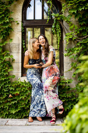 Pretty young women using mobile phone by old house with ivyの写真素材