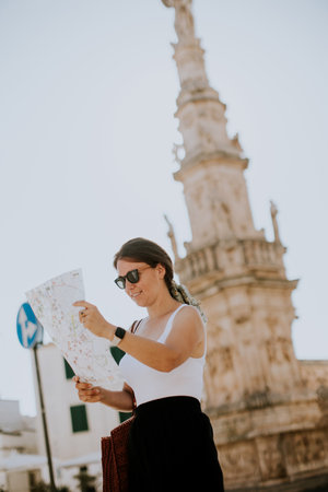 Female tourist with a city map by the Saint Oronzo statue in Ostuni, Italyの写真素材