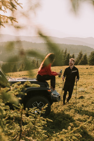 Handsome young couple relaxing by a terrain vehicle hood at countrysideの写真素材