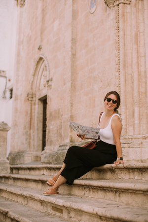 Female tourist with a city map by the church San Francesco dâAssisi in Ostuni, Italyの写真素材