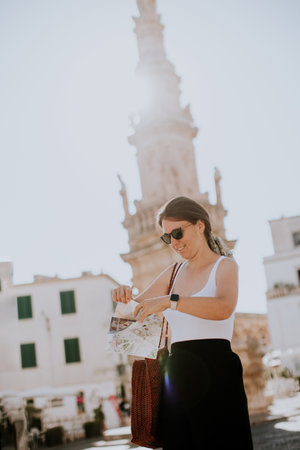 Female tourist with a city map by the Saint Oronzo statue in Ostuni, Italyの写真素材