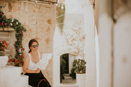 Female tourist with a paper city map on narrow streets of Ostuni, Italyの写真素材