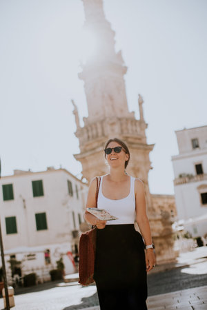 Female tourist with a city map by the Saint Oronzo statue in Ostuni, Italyの写真素材