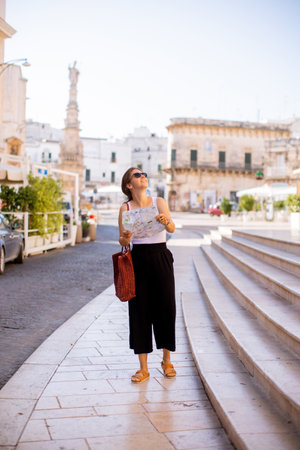 Female tourist with a city map by the Saint Oronzo statue in Ostuni, Italyの写真素材