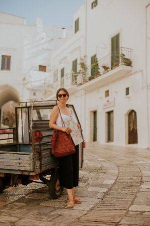 Female tourist with a paper city map on narrow streets of Ostuni, Italyの写真素材