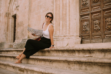 Female tourist with a city map by the church San Francesco dâAssisi in Ostuni, Italyの写真素材