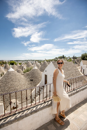 A young woman in a white dress and  hat on a sunny day during tourist visit in Alberobello, Italyの写真素材