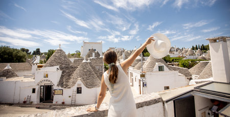 A young woman in a white dress and  hat on a sunny day during tourist visit in Alberobello, Italyの写真素材