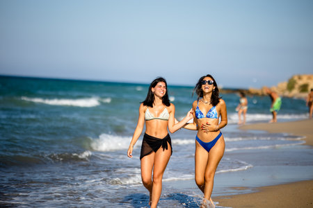 Two pretty young woman having fun on the seaside at hot summer dayの写真素材