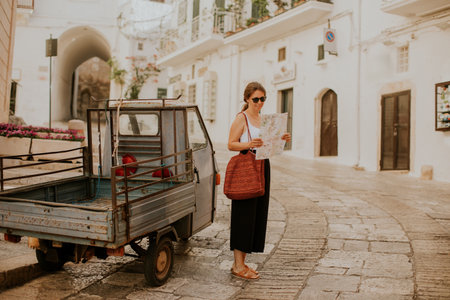 Female tourist with a paper city map on narrow streets of Ostuni, Italyの写真素材