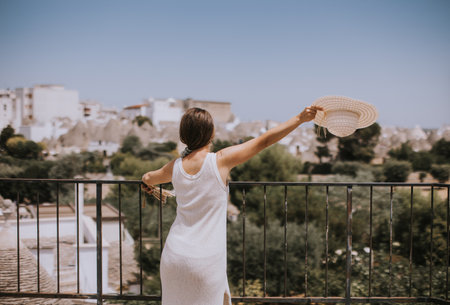 A young woman in a white dress and  hat on a sunny day during tourist visit in Alberobello, Italyの写真素材