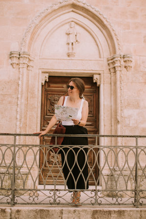Female tourist with a city map by the church San Francesco dâAssisi in Ostuni, Italyの写真素材
