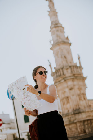 Female tourist with a city map by the Saint Oronzo statue in Ostuni, Italyの写真素材