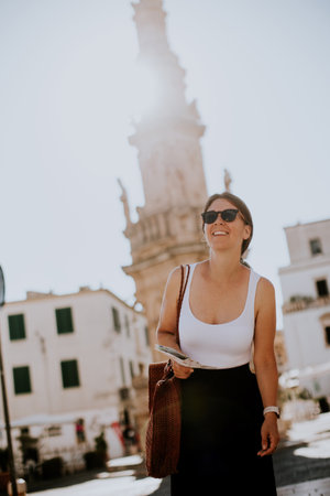 Female tourist with a city map by the Saint Oronzo statue in Ostuni, Italyの写真素材