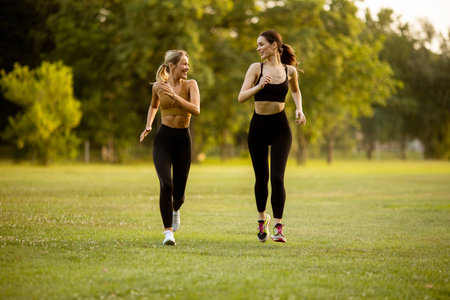 Two pretty young women running in the parkの写真素材