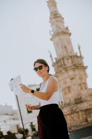 Female tourist with a city map by the Saint Oronzo statue in Ostuni, Italyの写真素材