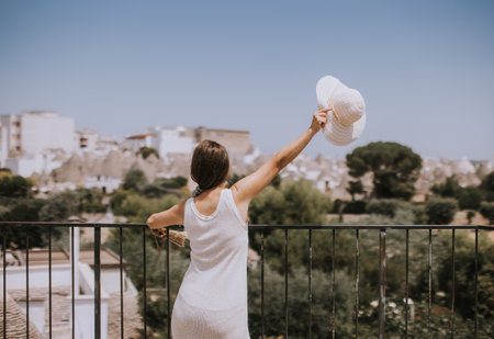 A young woman in a white dress and  hat on a sunny day during tourist visit in Alborebello, Italyの写真素材
