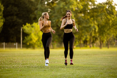 Two pretty young women running in the parkの写真素材