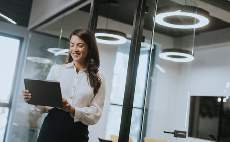 Young business woman with digital tablet standing in the modern officeの写真素材