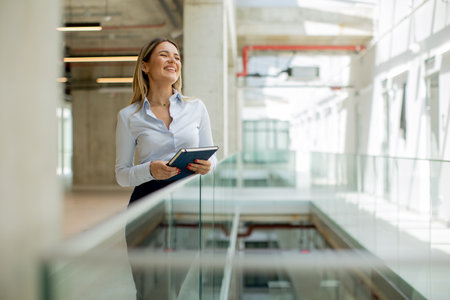 Young business woman with notebook standing in the modern office wallwayの写真素材
