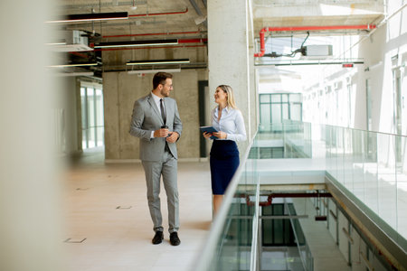 Young business couple holding paper notebook and discussing company strategyの写真素材