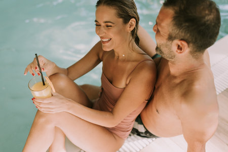 Handsome young couple relaxing by the indoor swimming poolの写真素材