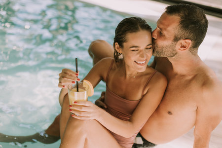 Handsome young couple relaxing by the indoor swimming poolの写真素材