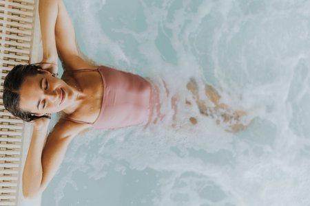 Pretty young woman relaxing in the indoor swimming poolの写真素材