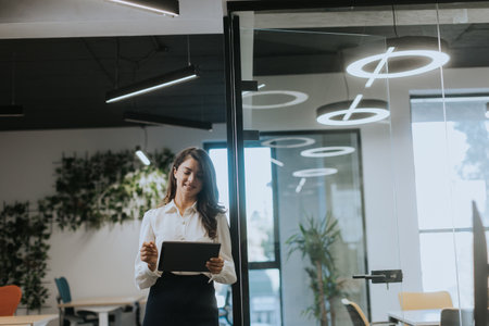 Young business woman with digital tablet standing in the modern officeの写真素材
