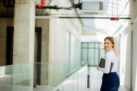 Young business woman with digital tablet walking in the modern office wallwayの写真素材