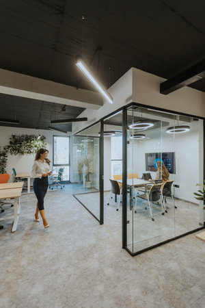Young business woman with digital tablet walking in the modern office