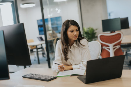 Pretty young business woman working on laptop in the modern officeの写真素材