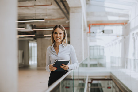 Young business woman with notebook standing in the modern office wallwayの写真素材