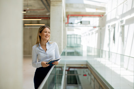 Young business woman with notebook standing in the modern office wallwayの写真素材