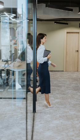 Young business woman with digital tablet walking in the modern office wallwayの写真素材