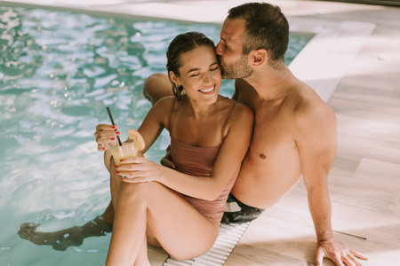Handsome young couple relaxing by the indoor swimming poolの写真素材