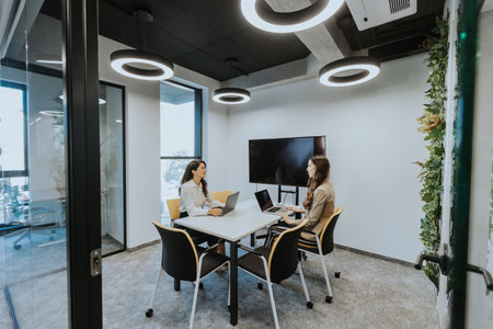 Young business women discussing in cubicle at the modern officeの写真素材