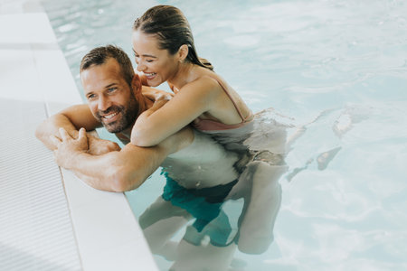 Handsome young couple relaxing in the indoor swimming poolの写真素材
