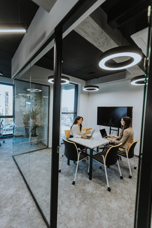 Young business women discussing in cubicle at the modern officeの写真素材