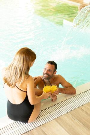 Handsome young couple relaxing by the indoor swimming poolの写真素材