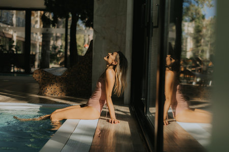 Pretty young woman relaxing by the indoor swimming poolの写真素材