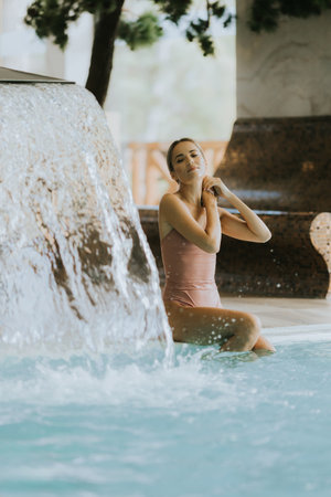 Pretty young woman relaxing by the indoor swimming poolの写真素材