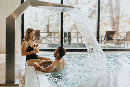 Handsome young couple relaxing by the indoor swimming poolの写真素材