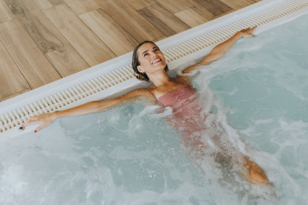 Pretty young woman relaxing in the indoor swimming poolの写真素材