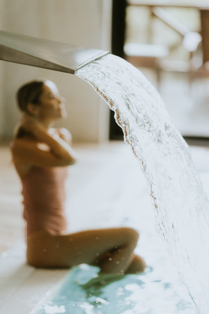 Pretty young woman relaxing by the indoor swimming pool